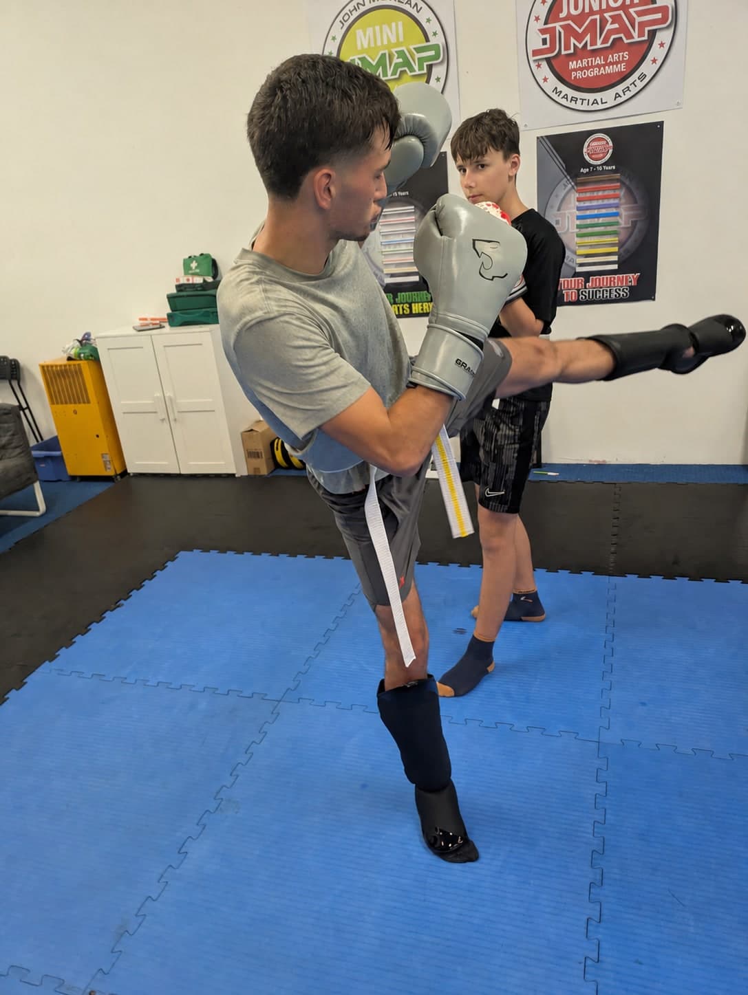 Teen martial arts student practising kickboxing with a coach